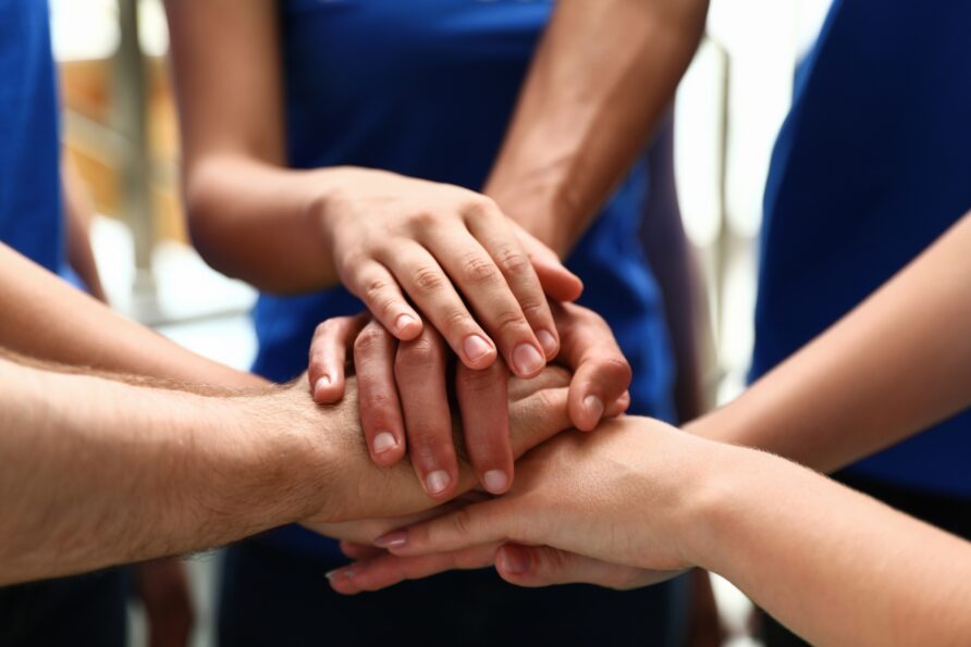 closeup of a group of volunteers joining hands together