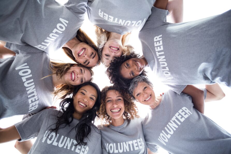 Group of volunteers in a circle all looking down at the camera