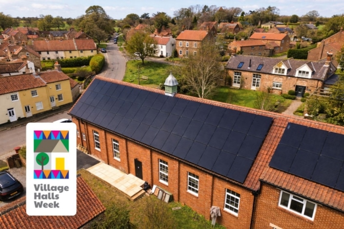 Aerial view of Whixley Village Hall with solar panels on its roof, surrounded by houses and trees, highlights community-led climate action. A Village Halls Week logo is in the lower left corner of the video image.