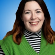 A smiling woman with shoulder-length brown hair, one of the featured speakers, wears a green jumper over a black and white striped polo neck, posed against a blue gradient background.