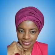 A woman wearing a deep pink headwrap and matching blazer, reminiscent of inspiring workshop hosts, smiles softly, resting her chin on her hand. She is against a blue gradient background and wears a ring and necklace.