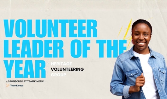 Smiling person in a denim jacket stands beside text reading Volunteer Leader of the Year, Heritage Volunteering Group, Sponsored by TeamKinetic on a light background, celebrating their prestigious Volunteer Award.