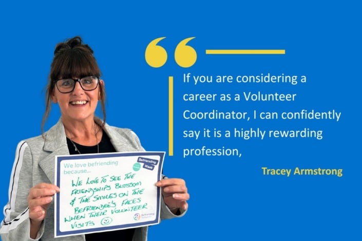 A smiling woman in glasses holds a sign about befriending, standing beside an inspiring quotation about helping others and launching a career as a Volunteer Co-ordinator. The quotation is attributed to Tracey Armstrong and set on a blue background.