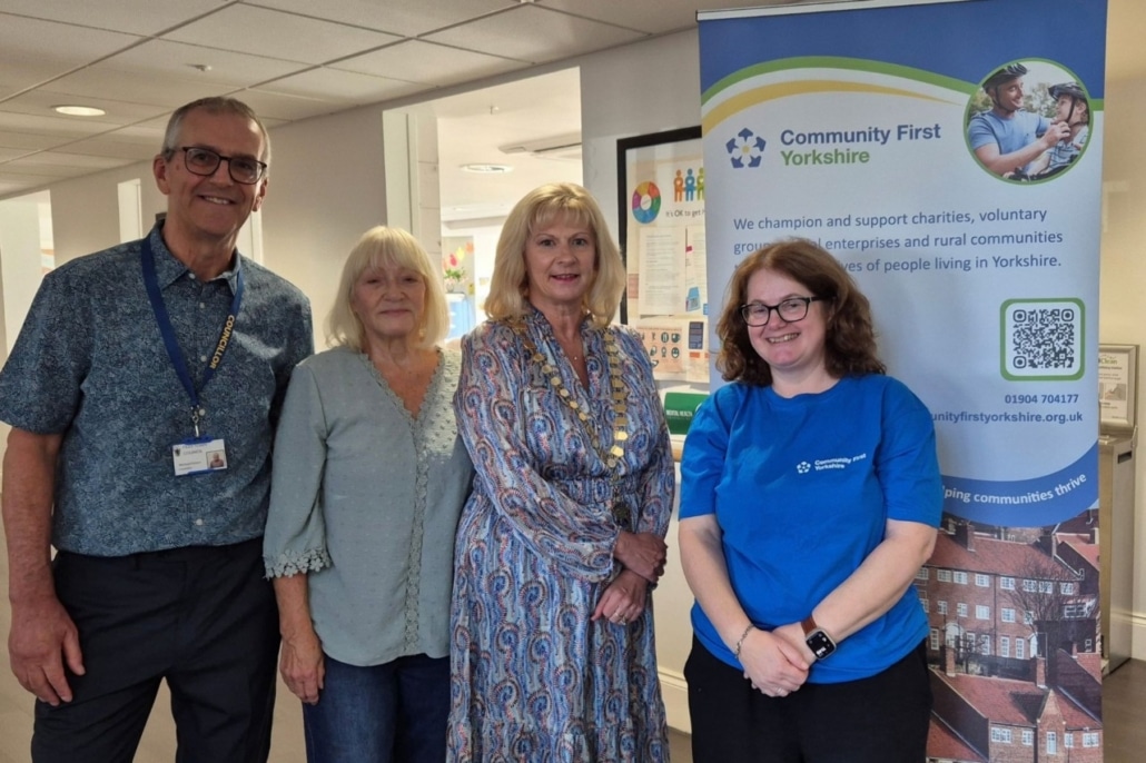 Four people stand in front of a Community First Yorkshire banner during a Filey community celebration.