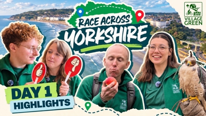 Four people in green jackets stand by a scenic coastal view with a beach. Text reads Race Across Yorkshire and Day 1 Highlights. One person holds a falcon; another eats an apple. Village Green logo in the corner.